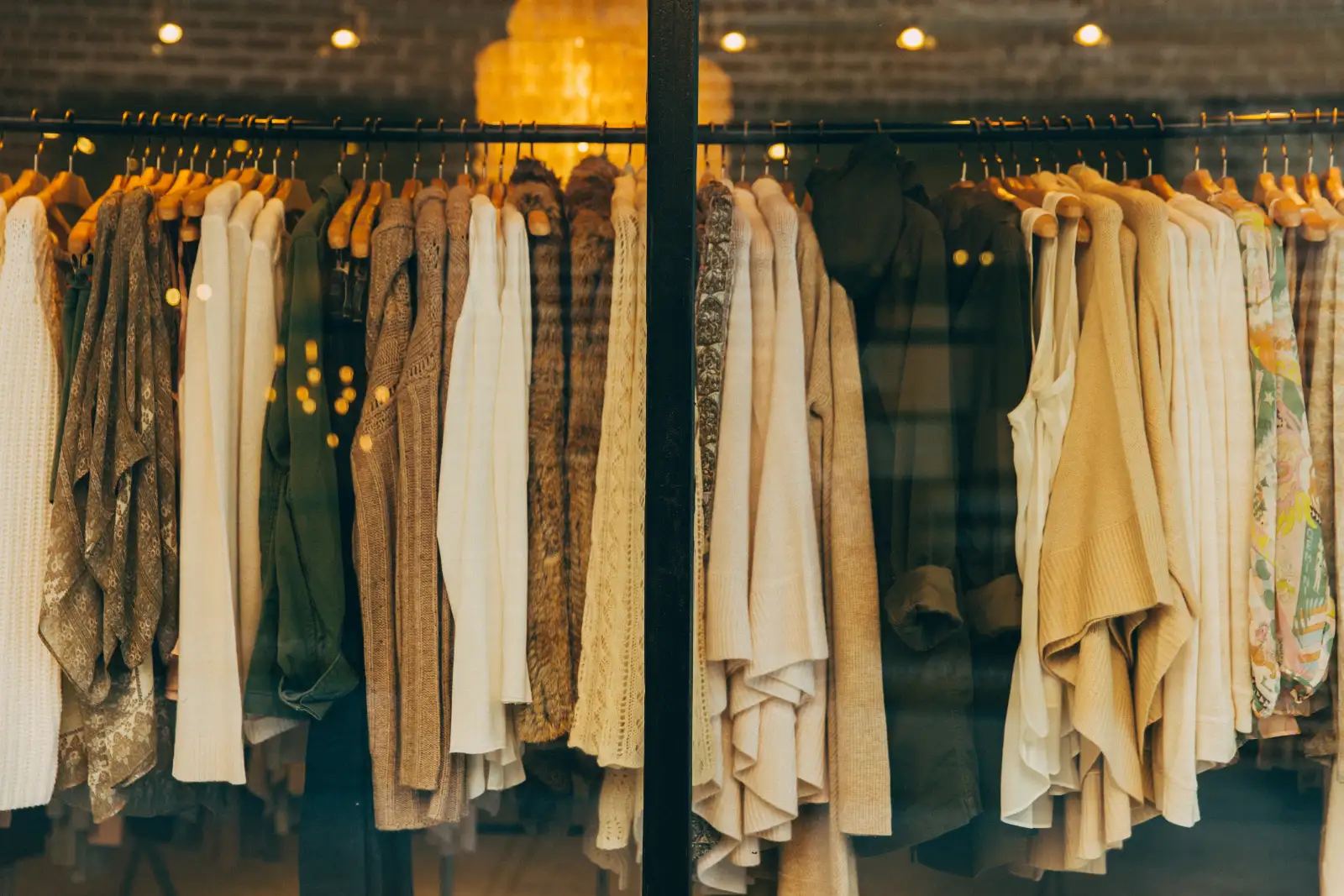 A rail of cream, tan and green knitwear on wooden hangers